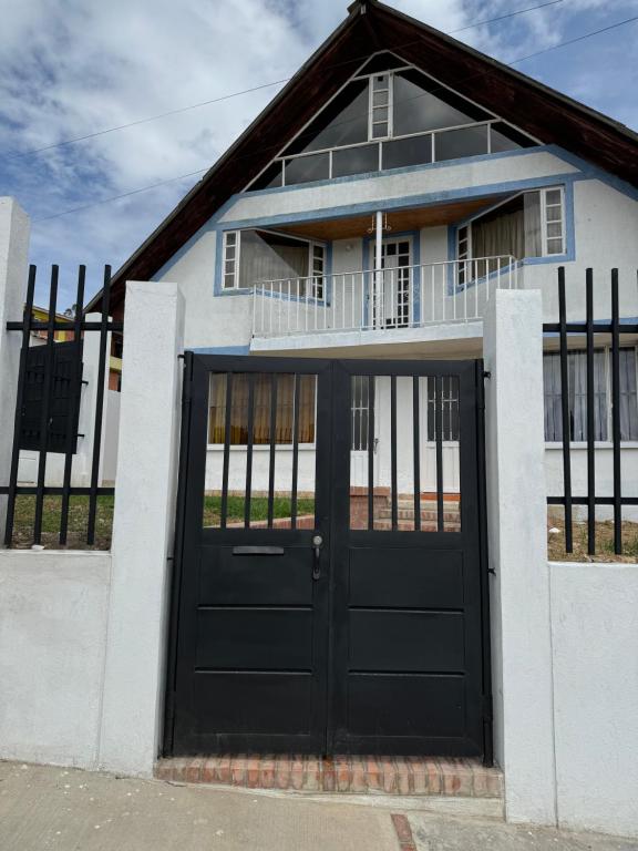 a white house with a black door at Cabaña El Recuerdo, Paipa in Paipa