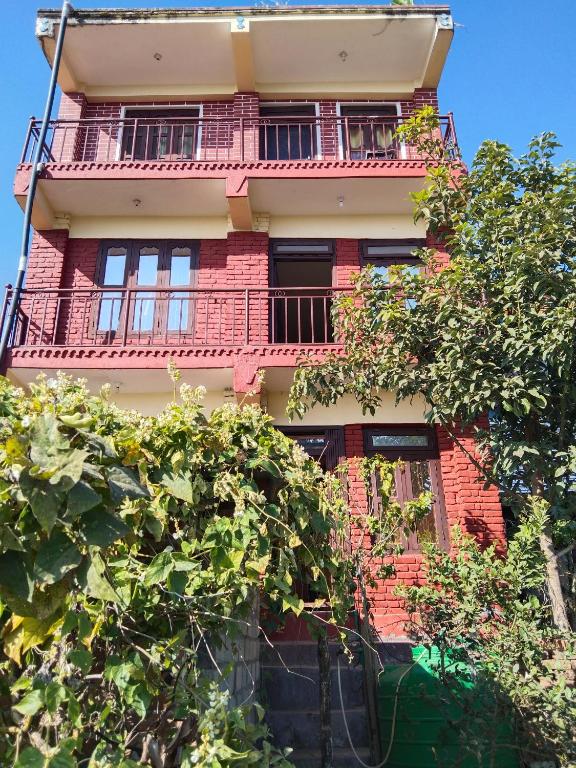um edifício alto em tijolo vermelho com uma varanda em GARIMA ORGANIC HOMESTAY em Bandipur