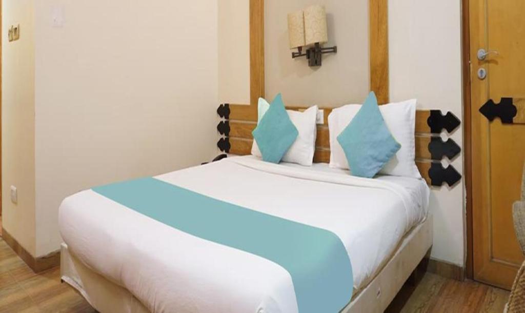 1 dormitorio con 1 cama blanca grande con almohadas azules en FabHotel Prime Deccan 8, en Pune
