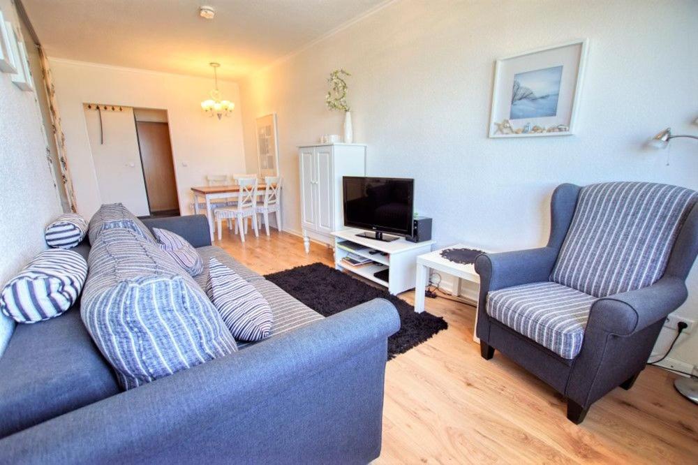 ein Wohnzimmer mit einem blauen Sofa und 2 Stühlen in der Unterkunft Strandhotel, App 5SH221 in Heiligenhafen