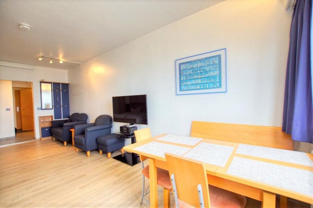 ein Wohnzimmer mit einem Tisch, Stühlen und einem Sofa in der Unterkunft Strandhotel, App 3SH219 in Heiligenhafen