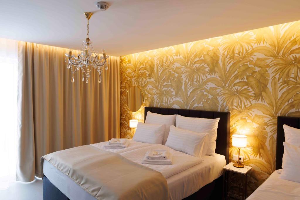 a bedroom with a large white bed with a chandelier at Villa Mala Praha Experience in the Center of Žilina in Žilina