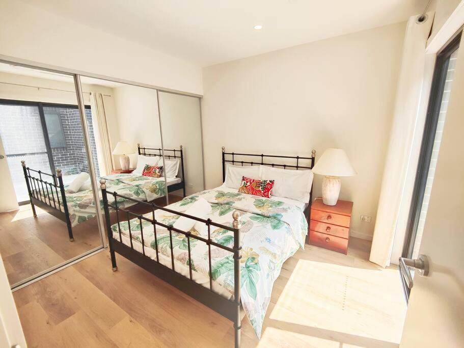 a bedroom with a bed and a lamp and a mirror at Brand new settled house near shops with Netflix in Weetangerra