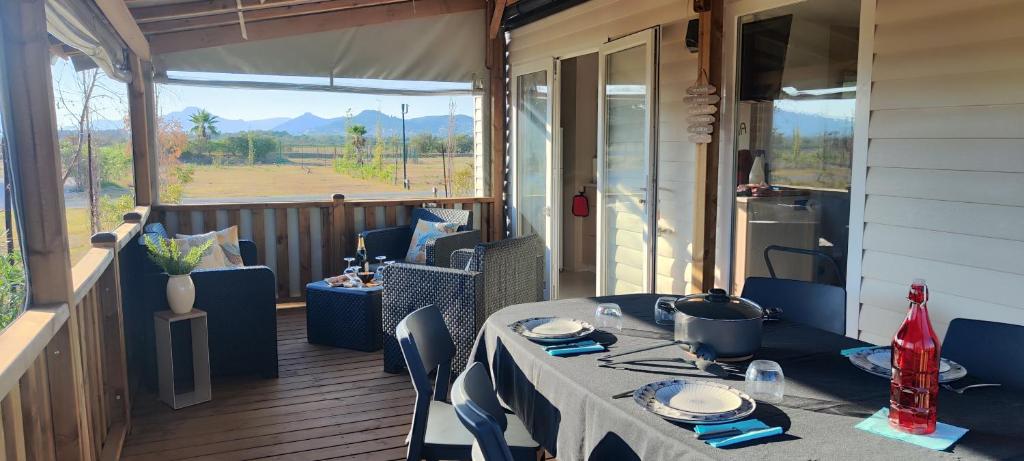 a table and chairs on a porch with a view at Mobil home neuf 4/6 P dans camping 4*- L'Almanarre Hyères - Idéal JO 2024 PACA in Hyères