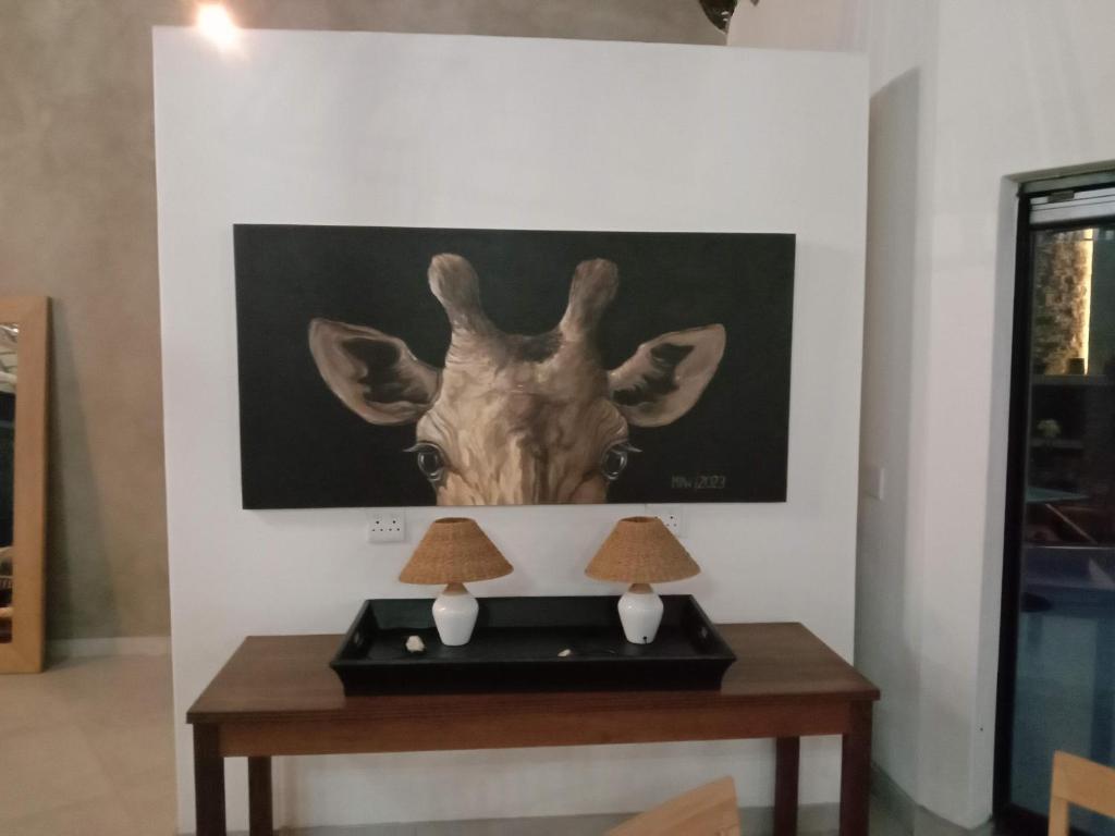 a table with a picture of a giraffe on the wall at Mologa River Lodge in Rust de Winter
