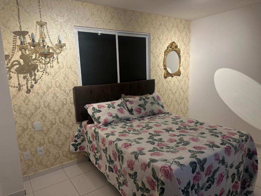 a bedroom with a bed with a floral comforter at Apt Real in Paulo Afonso