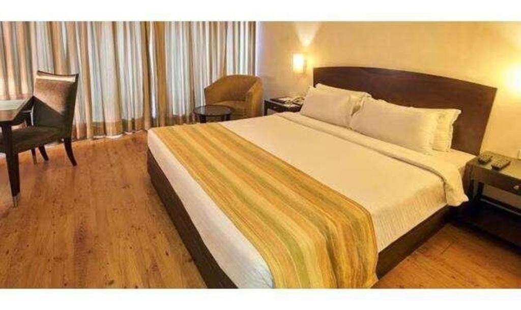 a hotel room with a large bed and a chair at FabHotel Prime Centurion in Pune