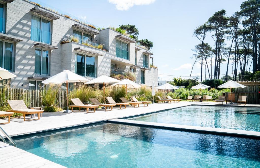 uma piscina com cadeiras e guarda-sóis ao lado de um edifício em Casagrande Hotel & Beach Club em José Ignacio