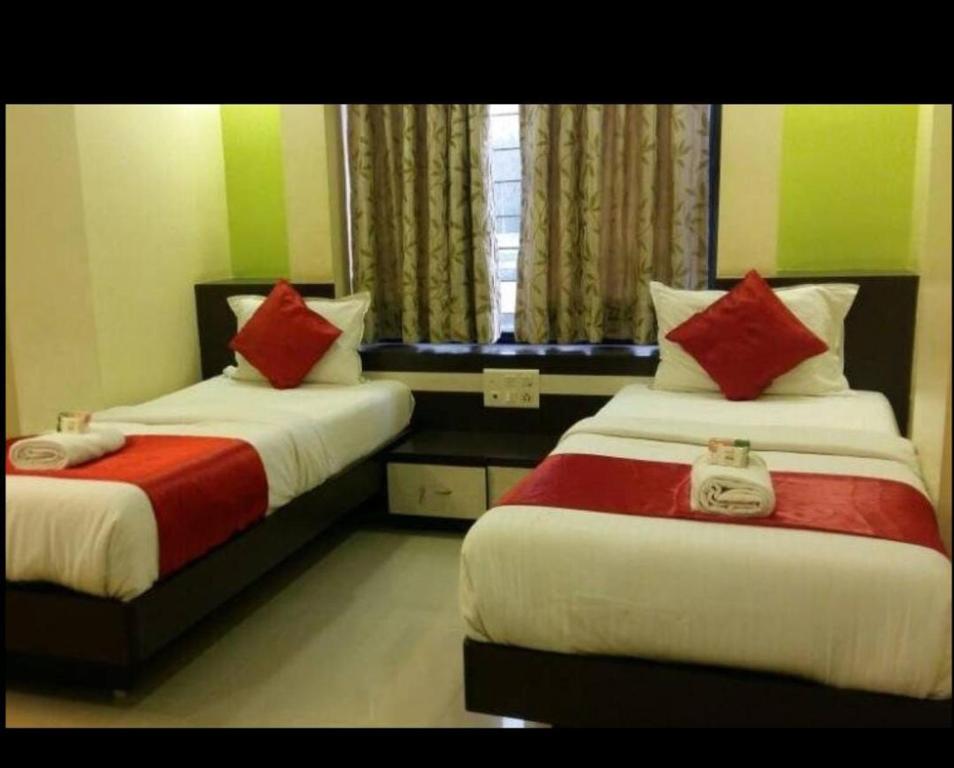 Un dormitorio con dos camas con almohadas rojas y blancas. en Nobel Studio, en Pune