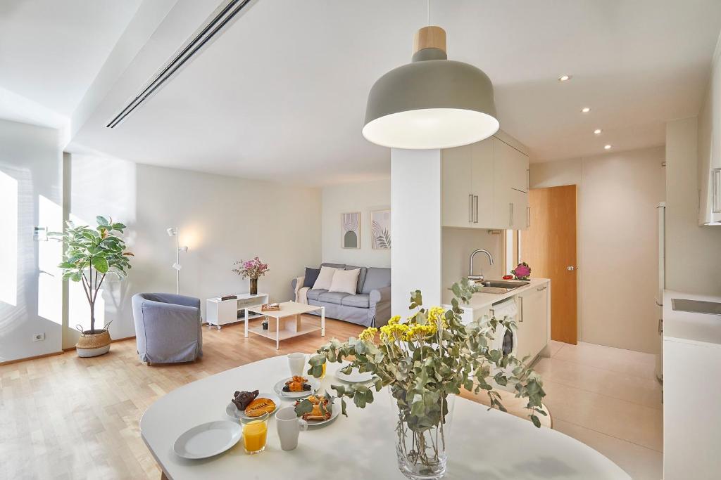 cocina y sala de estar con una mesa con flores en BBarcelona Plaça Universitat Flat, en Barcelona