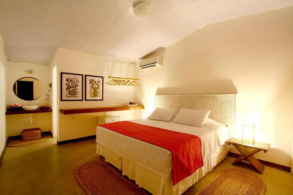 um quarto com uma cama grande e um cobertor vermelho em Pousada da Villa em Fernando de Noronha