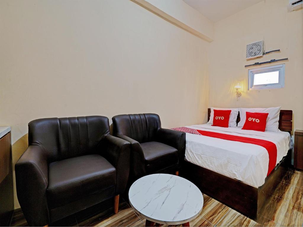 een kamer met een bed, een bank en een stoel bij OYO 92871 Ciparay Residence in Bandung