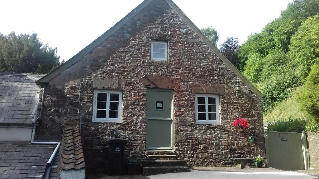 een stenen huis met een groene deur en ramen bij Anvil Cottage in Blakeney