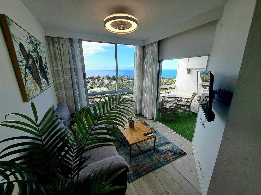 a living room with a couch and a large window at Ocean View Penthouse in Playa de las Americas