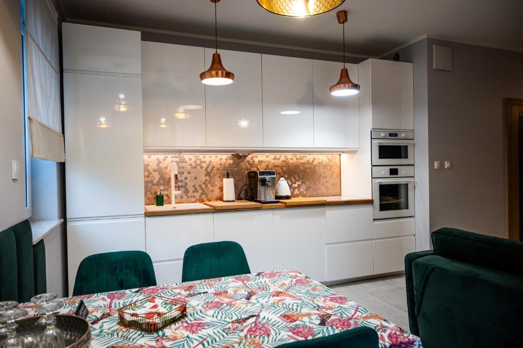 a kitchen with a table and green chairs at Apartament na Kaszubach in Kościerzyna