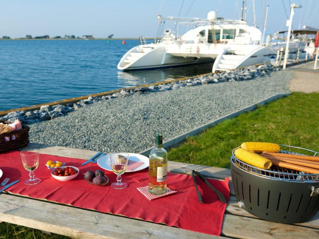 a picnic table with a bottle of wine and some food at Houseboat Seahorse in Heiligenhafen