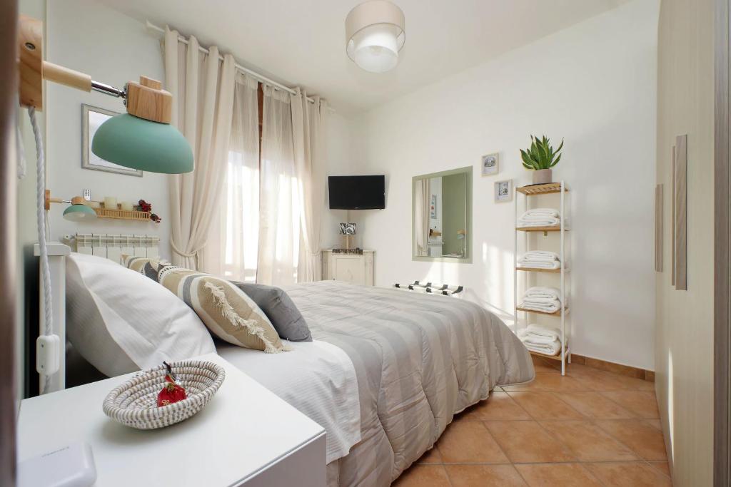 a white bedroom with a bed and a television at Summer&Winter Home by the sea in Fiumicino