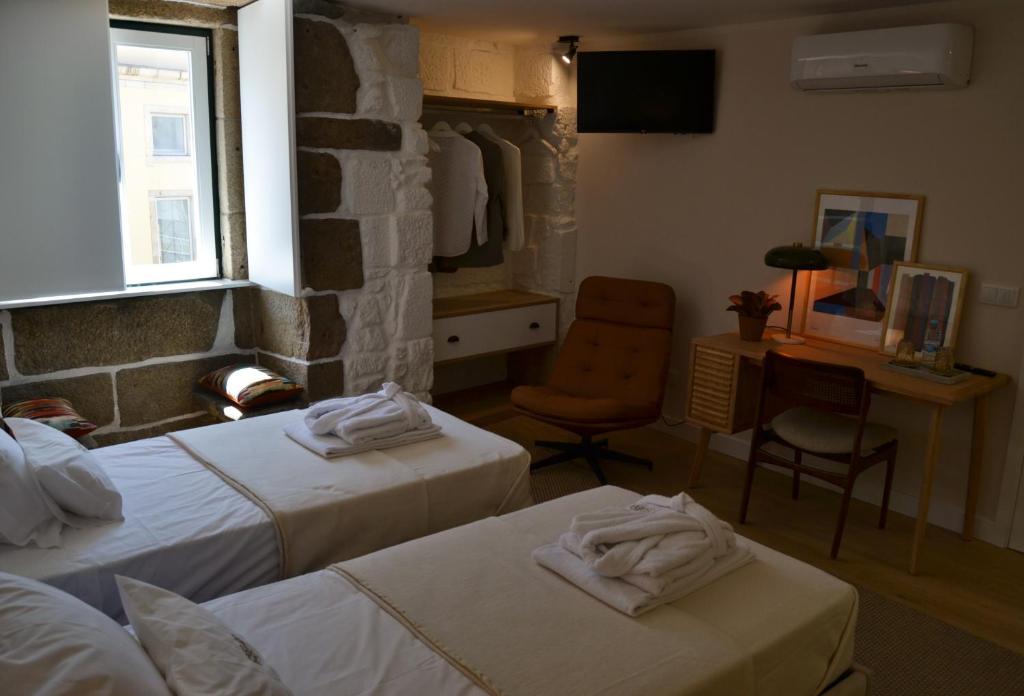 a room with two beds and a desk and a chair at Casa do Theatro Guest House in Barcelos
