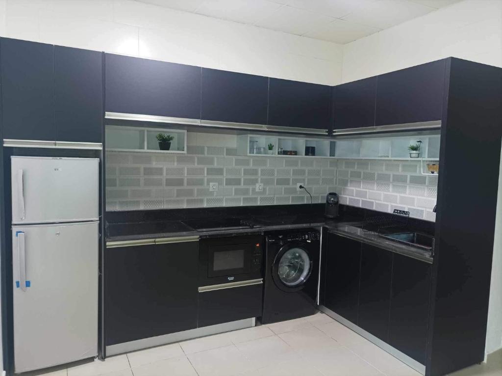 a kitchen with black cabinets and a washing machine at L’oranais in Oran