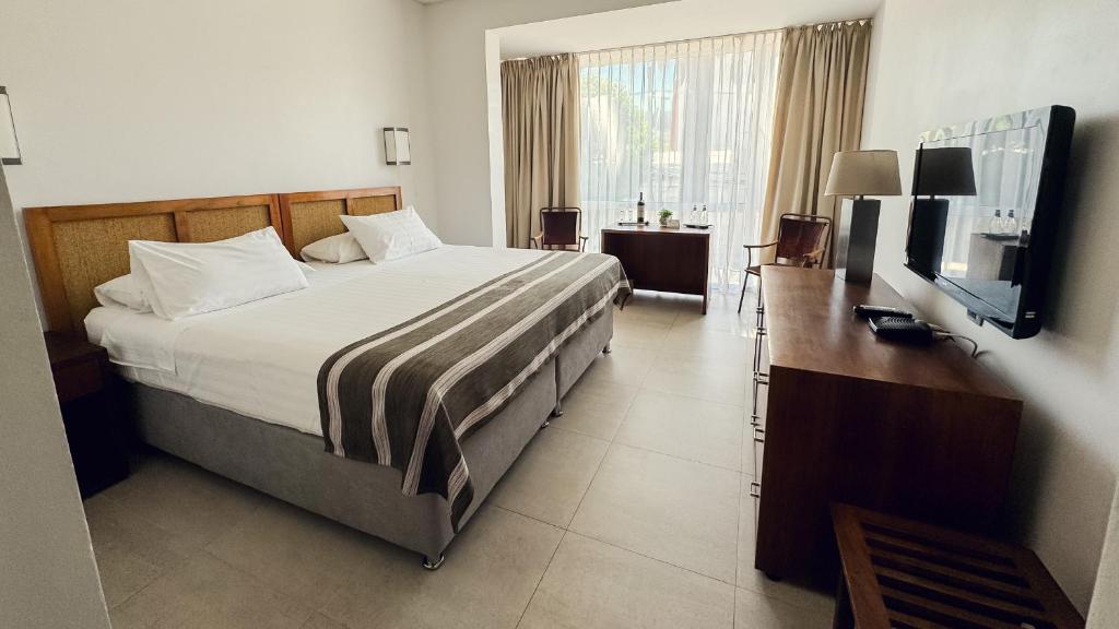 a bedroom with a bed and a flat screen tv at Hotel Boutique Raíces in Curicó