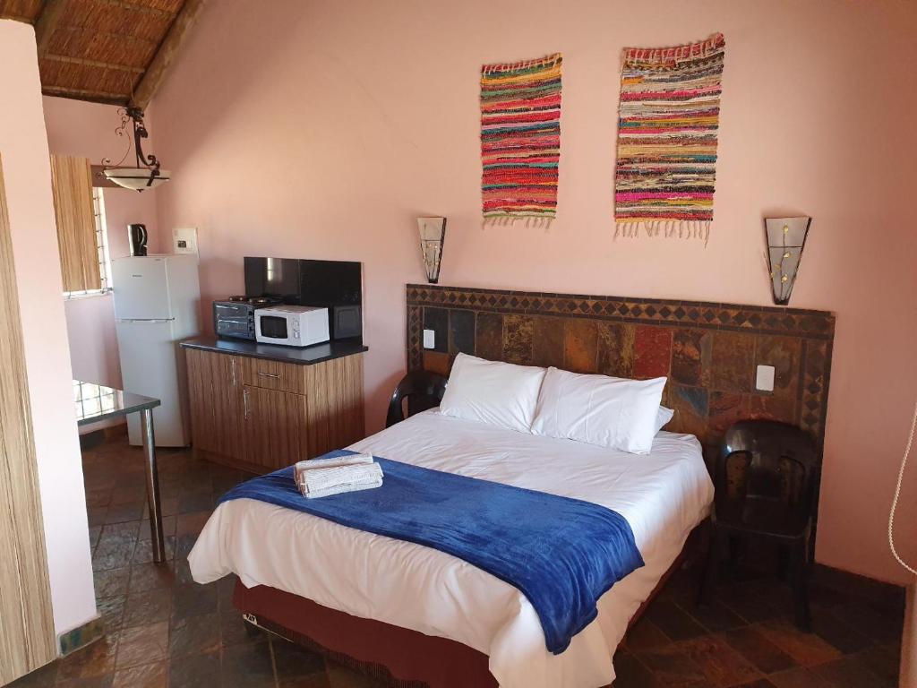 a bedroom with a bed and a microwave on the wall at Lagai Roi Guesthouse in Boshoek