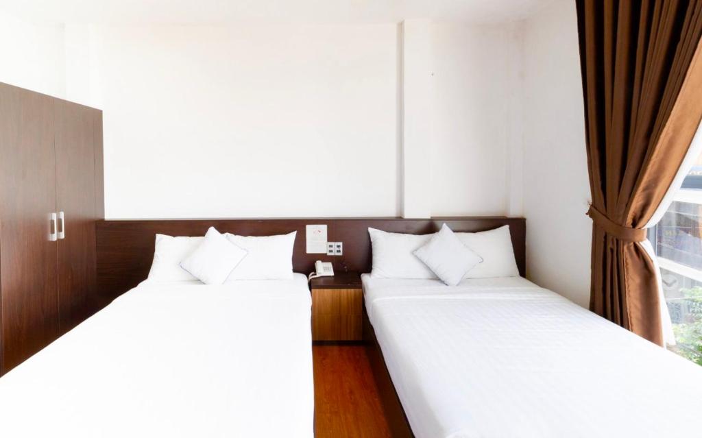 two twin beds in a room with a window at TTR Midtown View Hotel in Da Lat