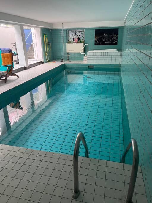 a large swimming pool with blue tile floors and blue tiles at Villa Casa Blanca mit Privatem Schwimmbad 26 grad und Sauna in Duisburg