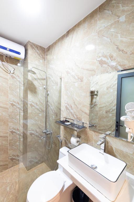 a bathroom with a shower and a toilet and a sink at TTR Midtown View Hotel in Da Lat