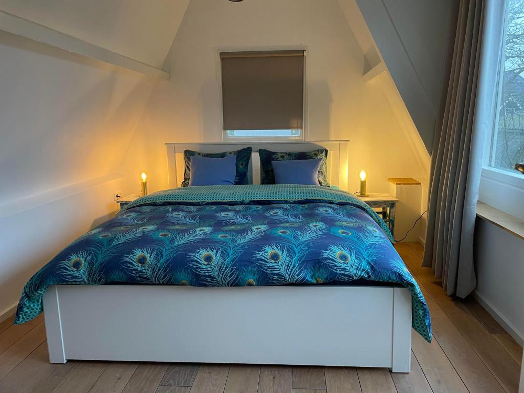 a bedroom with a large bed with a blue comforter at Het Heertje in Den Hoorn