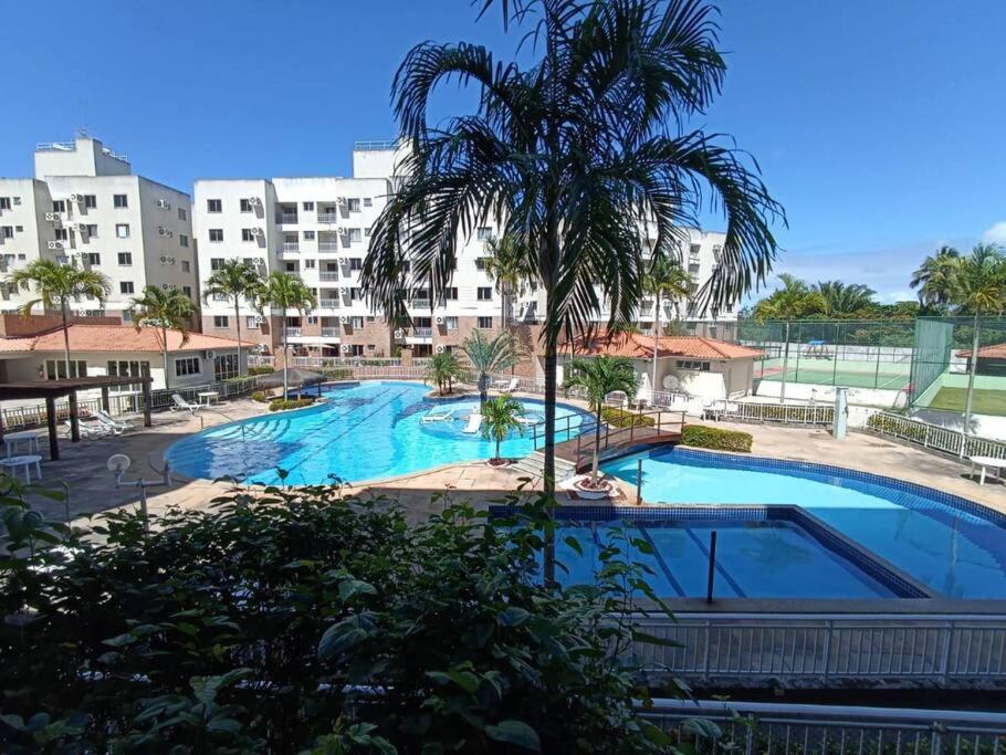 a large swimming pool with a palm tree in front of a building at Apartamento Clube 3/4 com Ar-condicionado in Aracaju