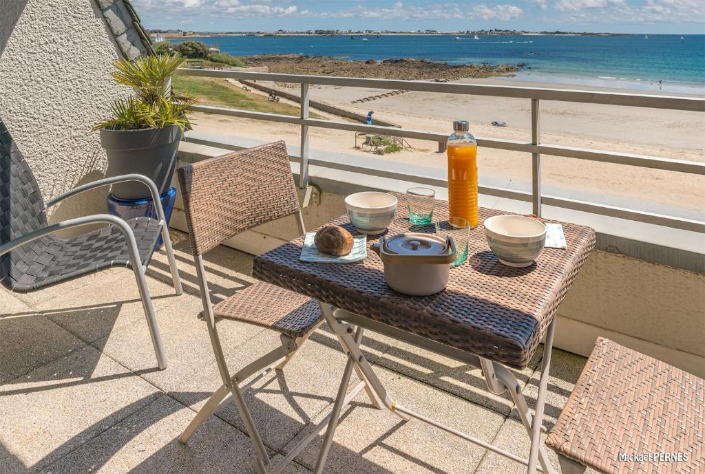 einen Tisch auf dem Balkon mit Blick auf den Strand in der Unterkunft RÉF 193 - LARMOR PLAGE Appartement de type T1 bis pleine vue mer in Larmor-Plage