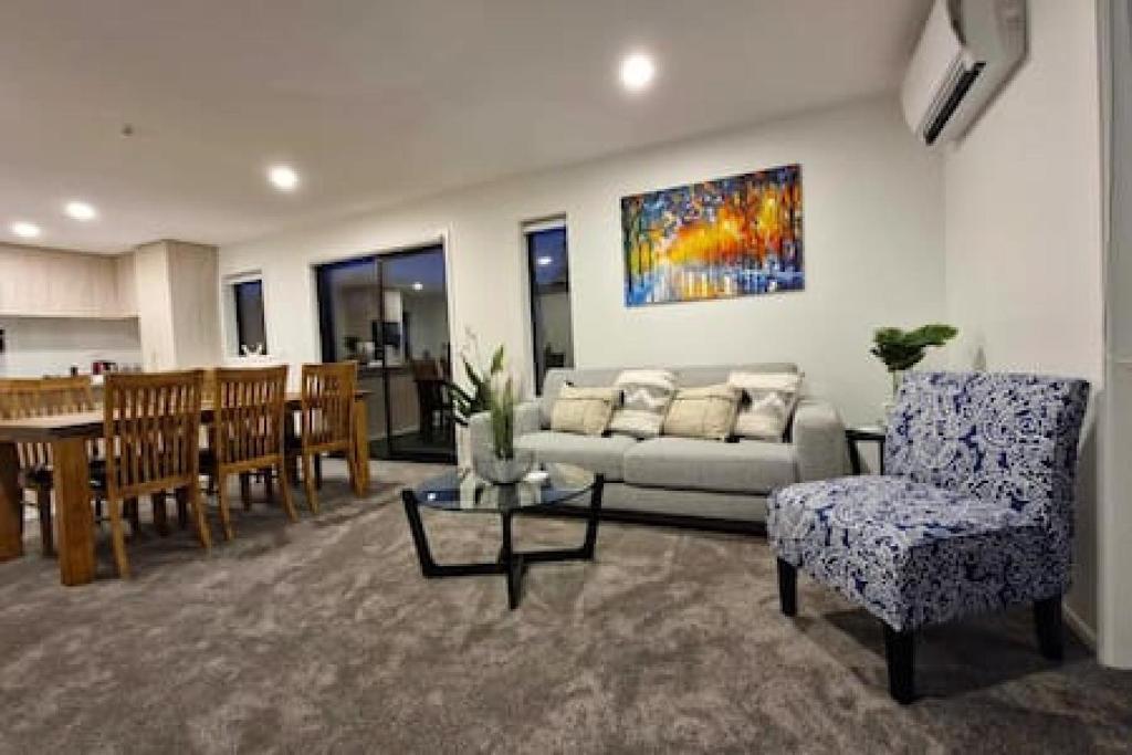 a living room with a couch and a dining room at Lovely Brand New Home 26 in Christchurch