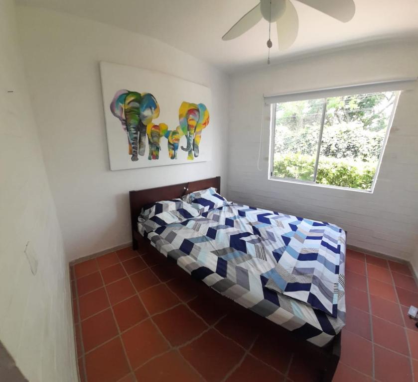 um quarto com uma cama com um edredão colorido e uma janela em Querido Palmar em Santa Fe de Antioquia