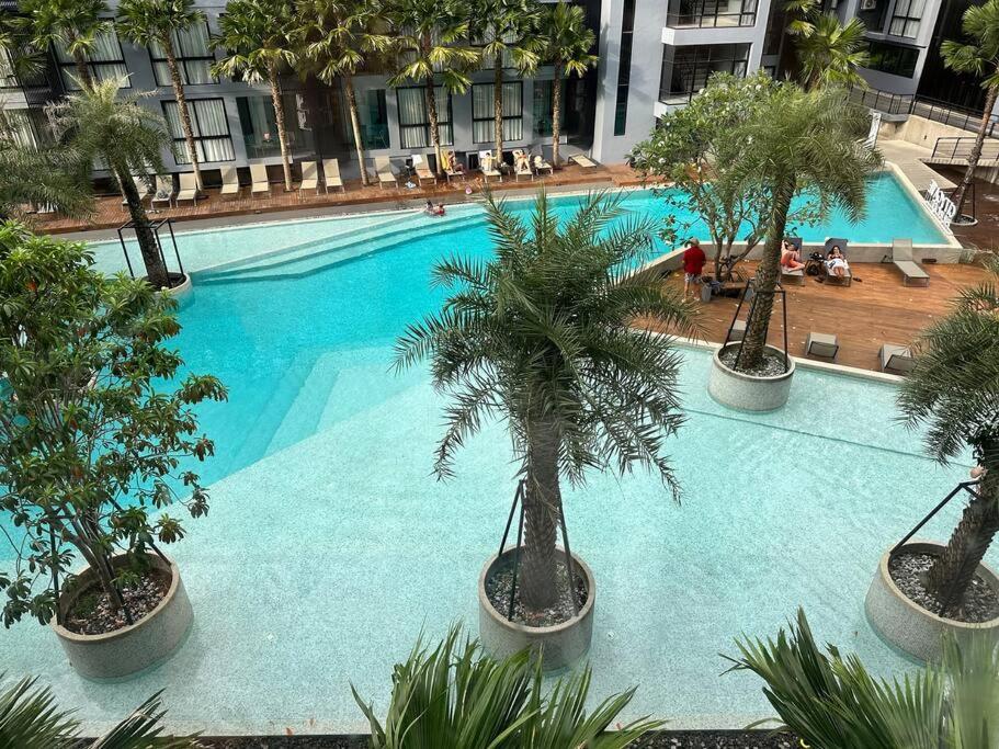 a large blue swimming pool with palm trees in it at Kamala poolview 2 bedroom suite in Kamala Beach