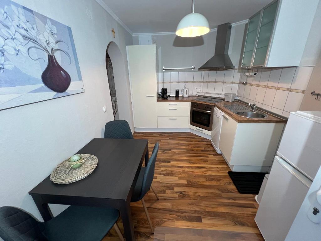 une cuisine avec une table et des chaises et une cuisine avec des placards blancs dans l'établissement Eifelurlaub Poredda, à Uersfeld