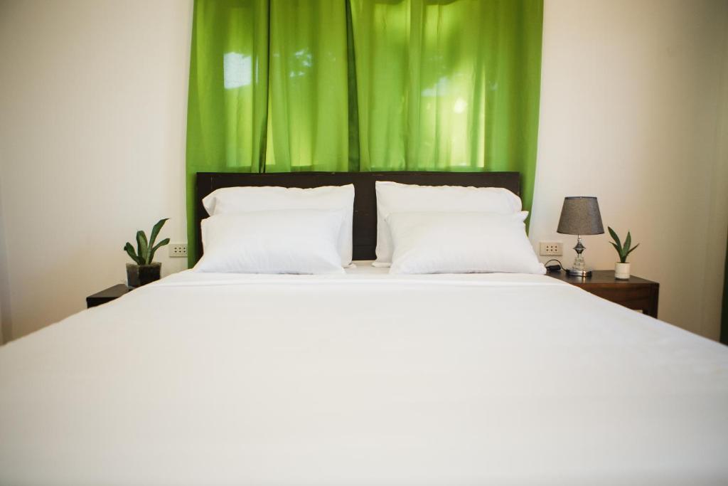 a bedroom with a white bed with green curtains at Nana's Beach Surigao in Surigao