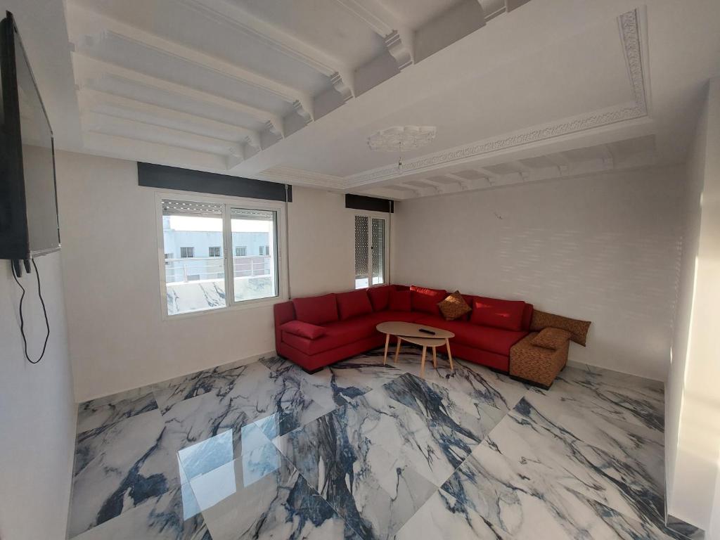 ein Wohnzimmer mit einem roten Sofa und einem Tisch in der Unterkunft Tanja balya 21 in Tangier