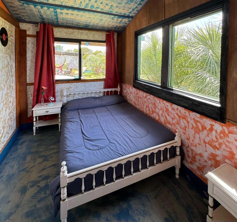uma cama num quarto com duas janelas em Biodiversidad posada familiar em La Pedrera