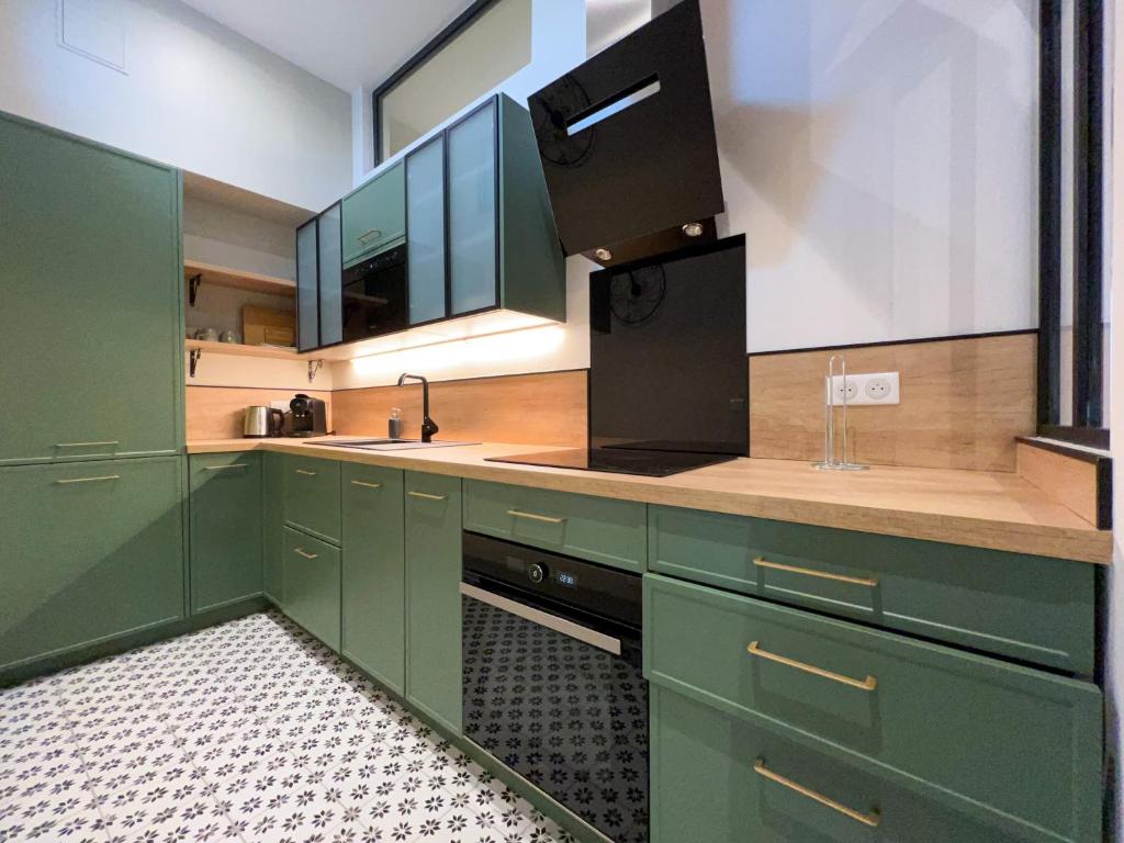 eine Küche mit grünen Schränken und einem Waschbecken in der Unterkunft Beautilful flat in Saint germain en laye in Saint-Germain-en-Laye