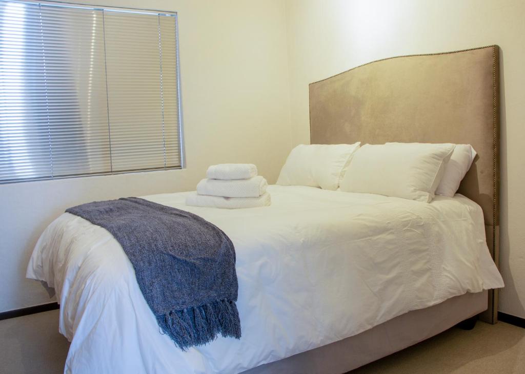 a bedroom with a bed with white sheets and pillows at Eden Suites in Sandton