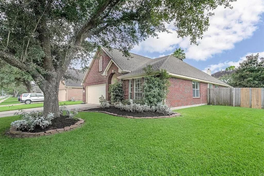 a house with a green yard with a tree at Fully Furnished Ranch Style Home Close To Houston in Pearland