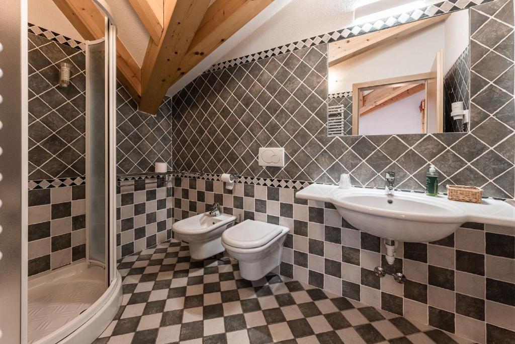 bagno con lavandino, servizi igienici e specchio di Hotel Sasso Rosso a Commezzadura