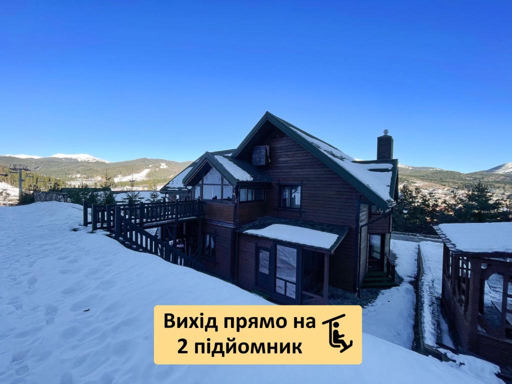 uma casa na neve com um sinal na frente em Nordian chalet next to Bukovel ski lift em Bukovel