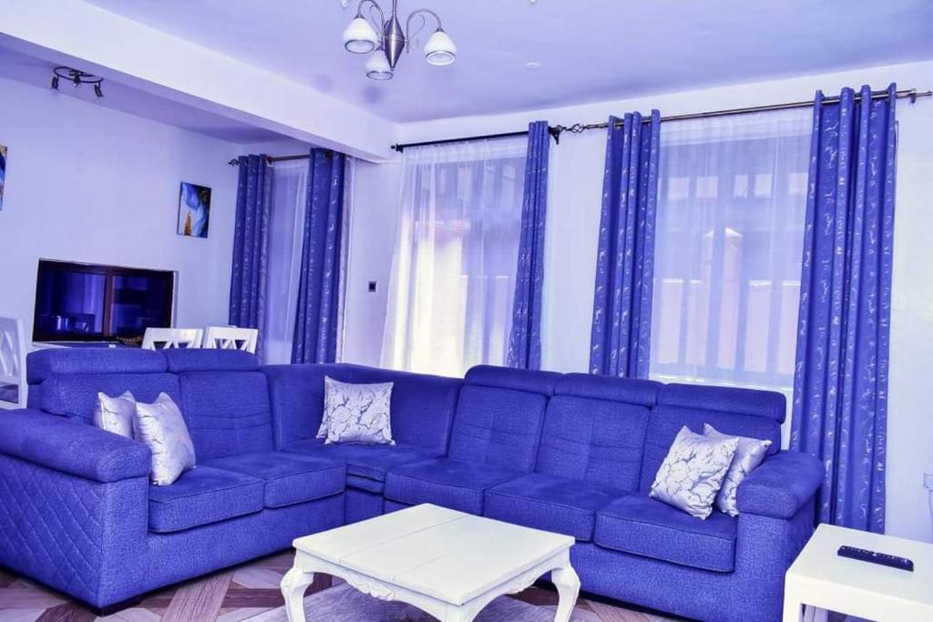 um sofá azul numa sala de estar com cortinas azuis em Motema AirBnB em Kisumu