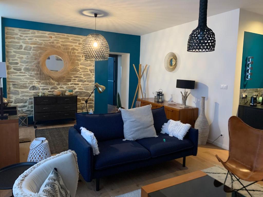 - un salon avec un canapé bleu et un mur en pierre dans l'établissement Appartement en RDC chaleureux à 100m des plages et du centre ville, à Concarneau