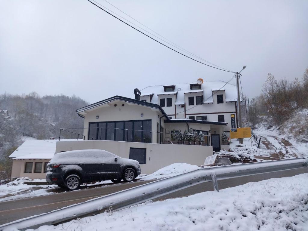 a car parked in front of a house in the snow at Apartmani Sunce Stara planina in Crni Vrh