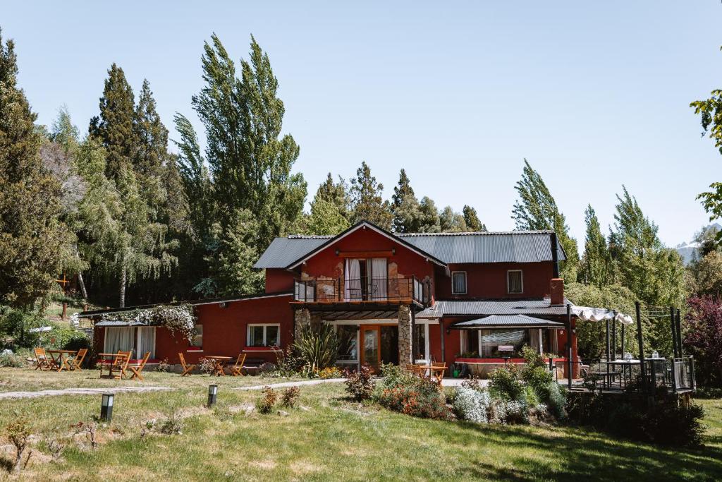 ein rotes Haus mit Bäumen im Hintergrund in der Unterkunft Equs Posada de Campo in San Carlos de Bariloche