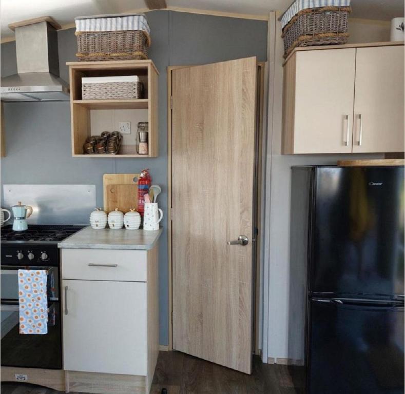a kitchen with a black refrigerator and white cabinets at Great 8 Berth Caravan At Sand Le Mere In Yorkshire Ref 71001i in Tunstall