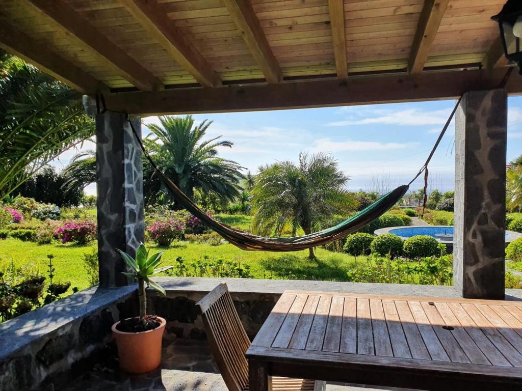 a hammock on a patio with a view of a pool at WelcomeBuddy - Traumgarten Rustic House (Sunset) in Várzea