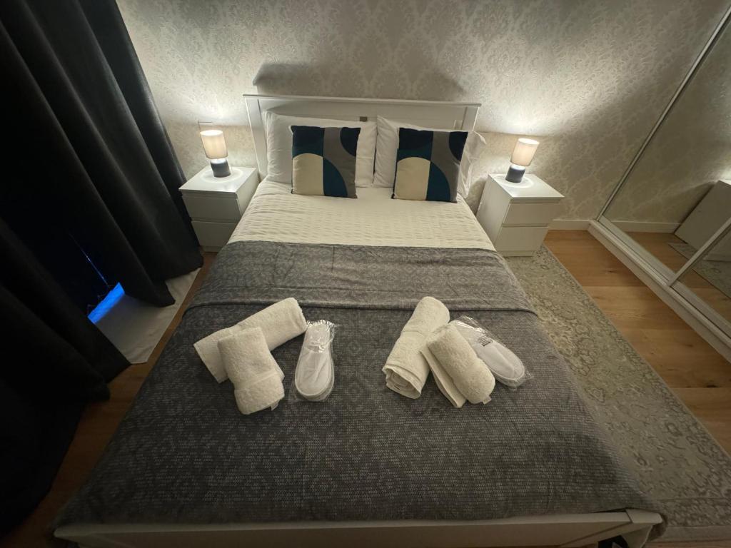 a bedroom with a bed with three pairs of shoes on it at Sela House - Luton Airport in Luton